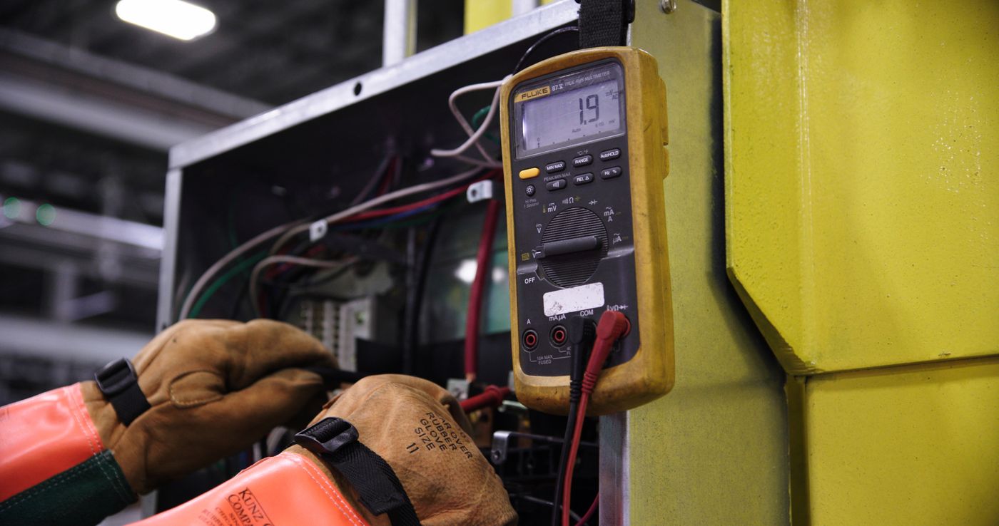 Electrician testing an industrial electrical panel with a meter